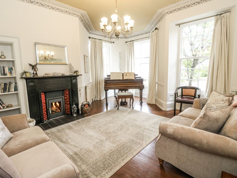 A living room with a piano and fireplace at Rowan Tree House in Brechin