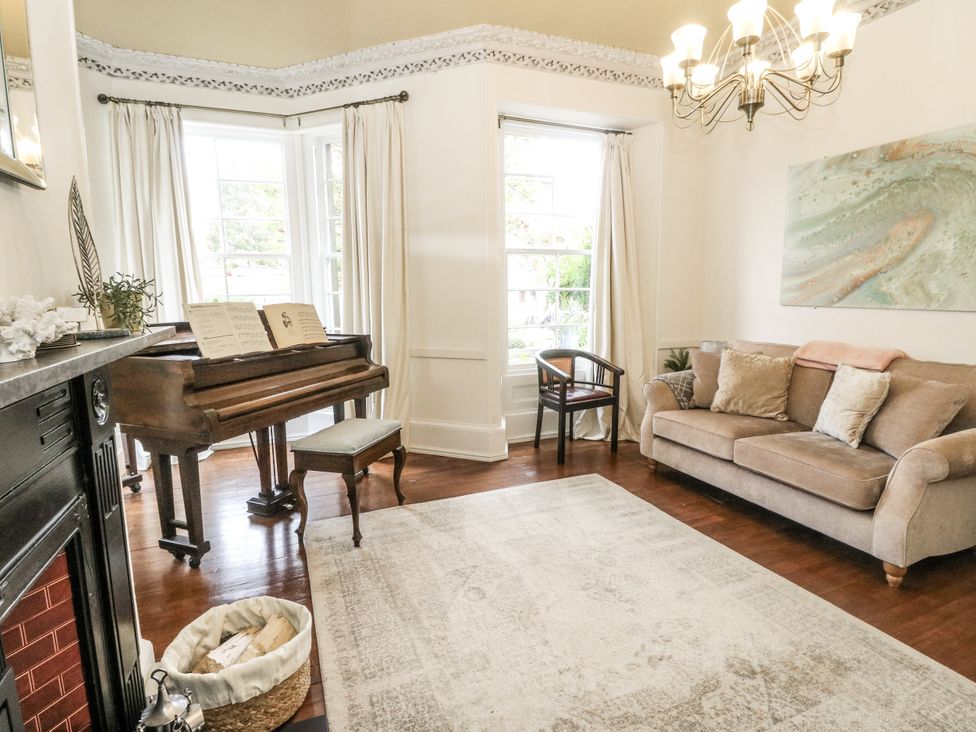 A living room with a piano and sofa at Rowan Tree House in Brechin