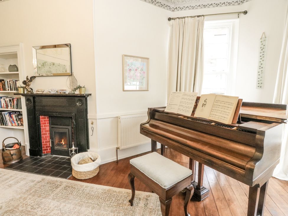 A living room with a piano and fireplace at Rowan Tree House Brechin