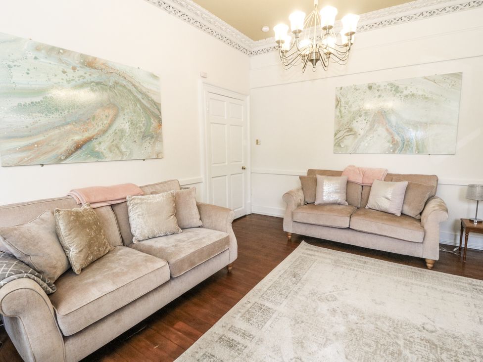 A living room with sofas and paintings at Rowan Tree House in Brechin