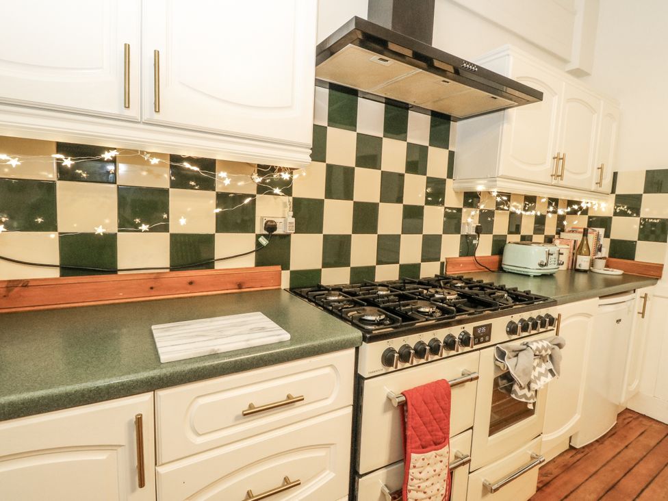 A kitchen with cabinets, stove, and countertop at Rowan Tree House in Brechin