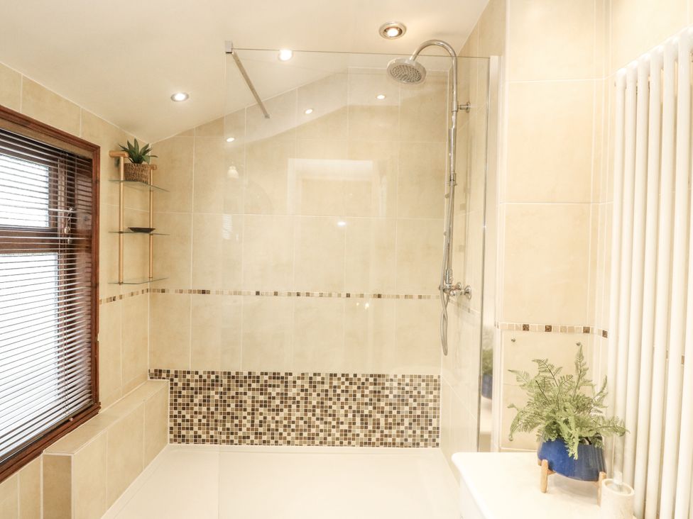 A bathroom with a shower and bathtub at Rowan Tree House in Brechin