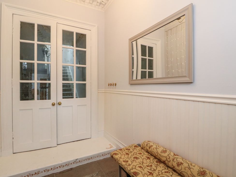 An entrance hall with a mirror and a double door at Rowan Tree House Brechin