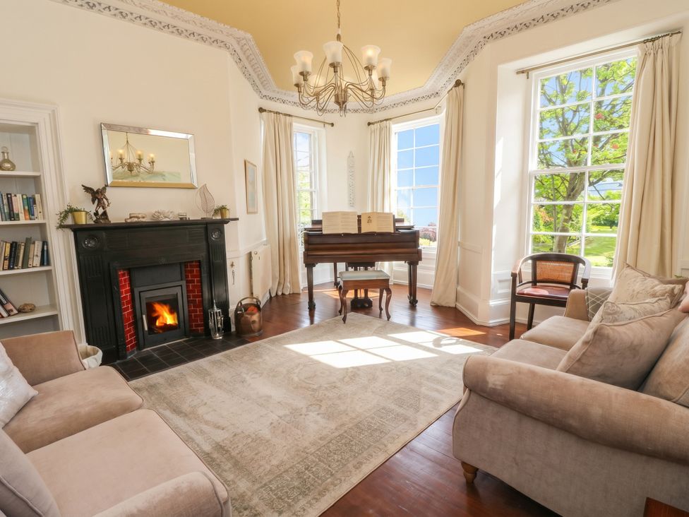 A living room with a piano and fireplace at Rowan Tree House in Brechin