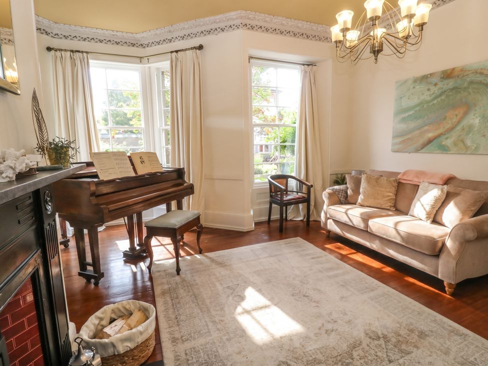 A living room with a piano and a sofa at Rowan Tree House in Brechin