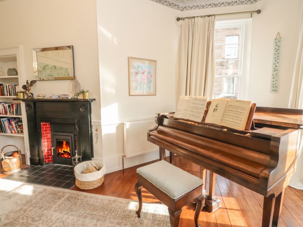 A living room with a piano and a fireplace at Rowan Tree House in Brechin