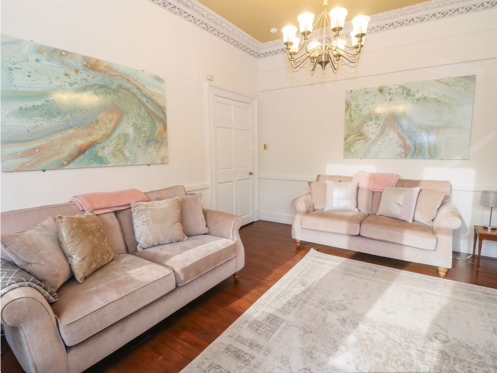 A living room with sofas and artwork at Rowan Tree House in Brechin