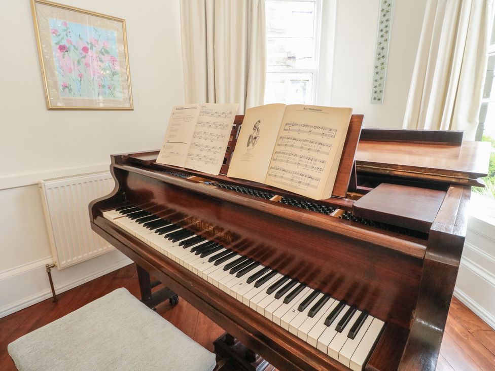 A piano with sheet music in a music room at Rowan Tree House Brechin