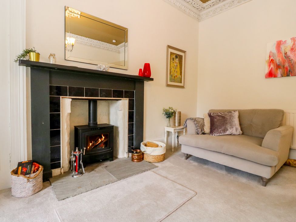 A living room with a fireplace and a chair at Rowan Tree House Brechin