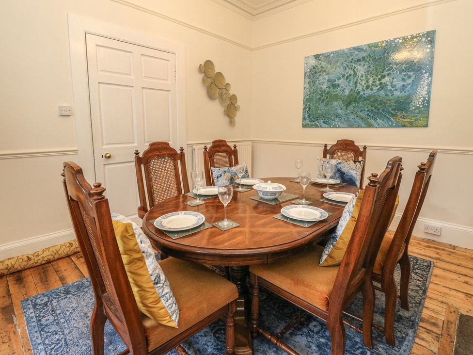 A dining room with a round table and chairs at Rowan Tree House Brechin