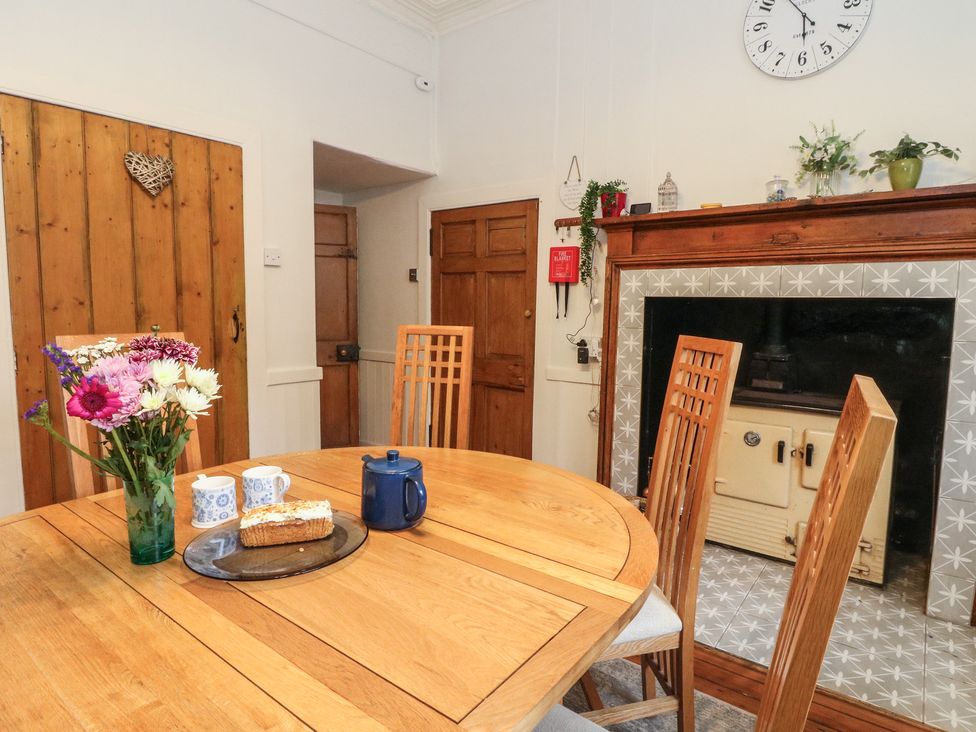 A kitchen with a table, chairs, a flower vase, and a fireplace at Rowan Tree House in Brechin