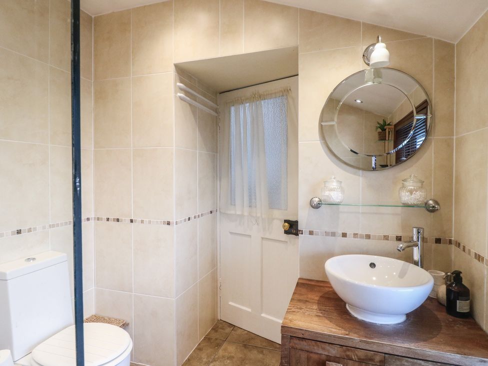 A bathroom with a sink, toilet, and mirror at Rowan Tree House in Brechin