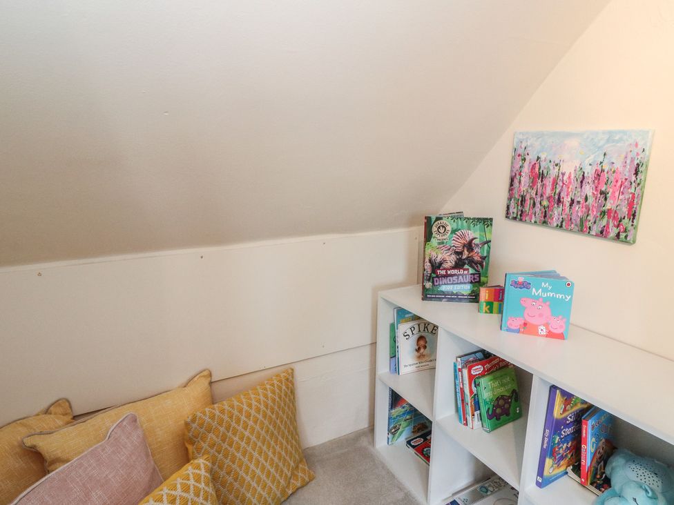 A reading nook with shelves of books and pillows at Rowan Tree House Brechin