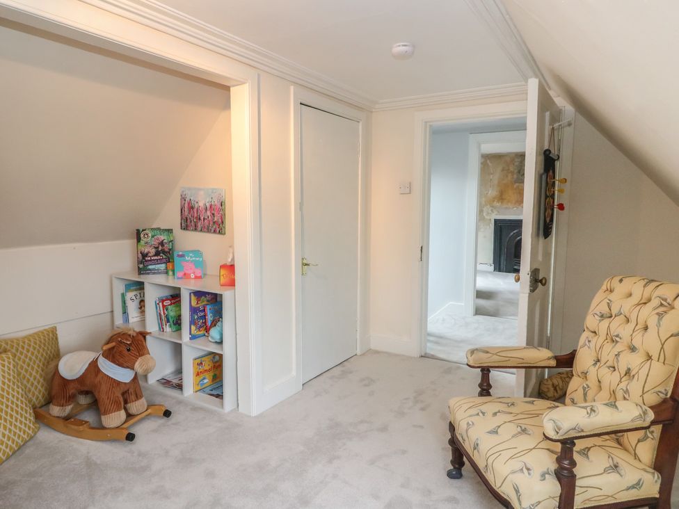 A playroom with a bookshelf and rocking horse at Rowan Tree House in Brechin