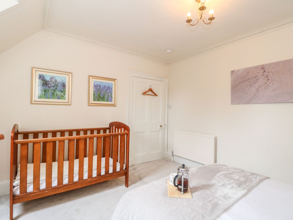 A bedroom with a crib and bed at Rowan Tree House Brechin