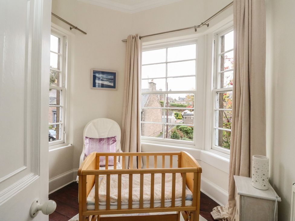 A nursery with a cot and windows at Rowan Tree House in Brechin