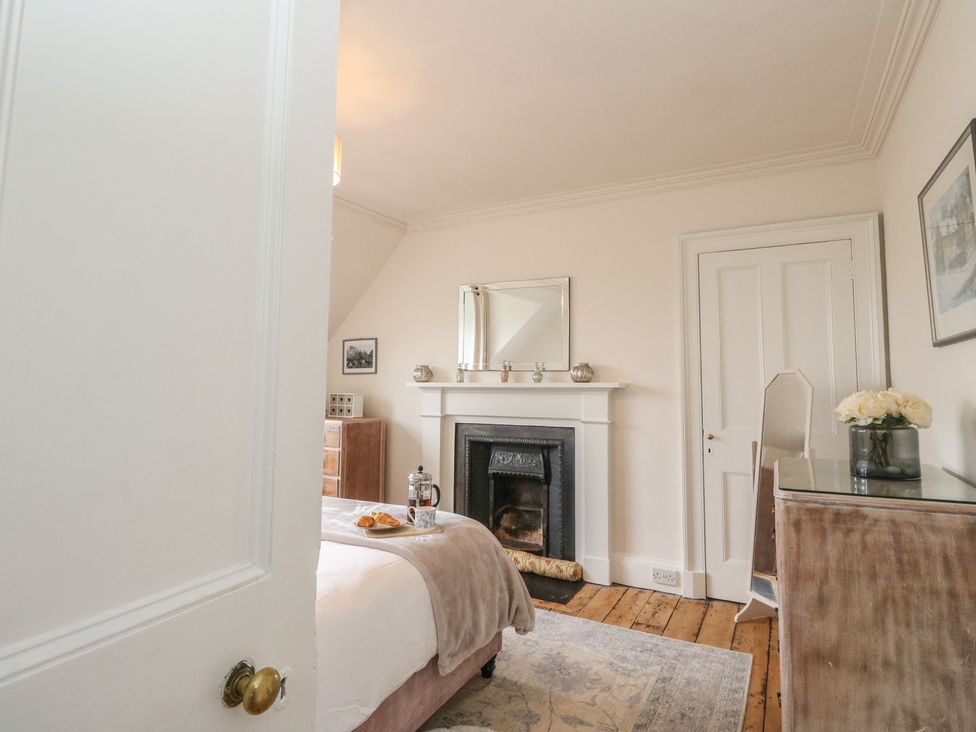 A bedroom with a fireplace and mirror at Rowan Tree House Brechin