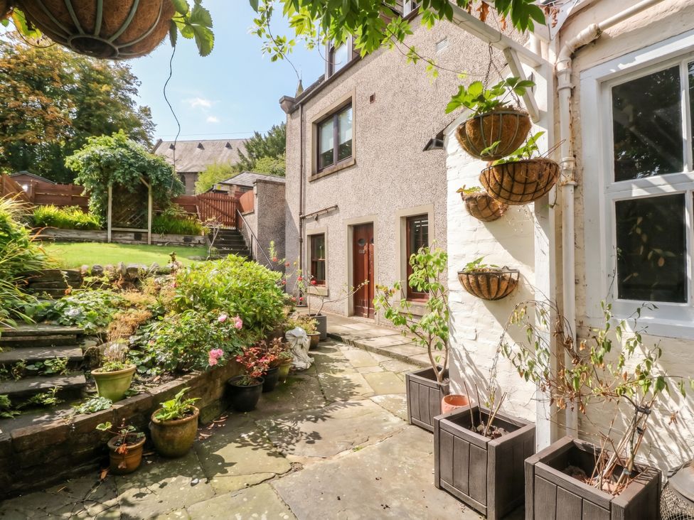 A garden with flower pots and a house at Rowan Tree House Brechin