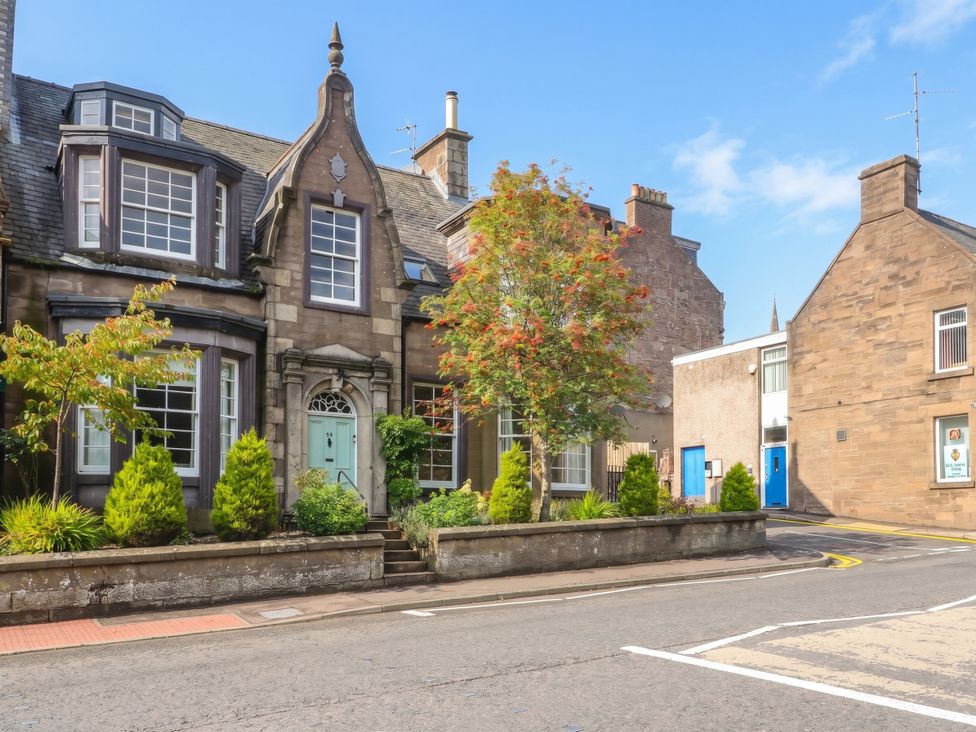 A building with a tree and bushes in front at Rowan Tree House in Brechin