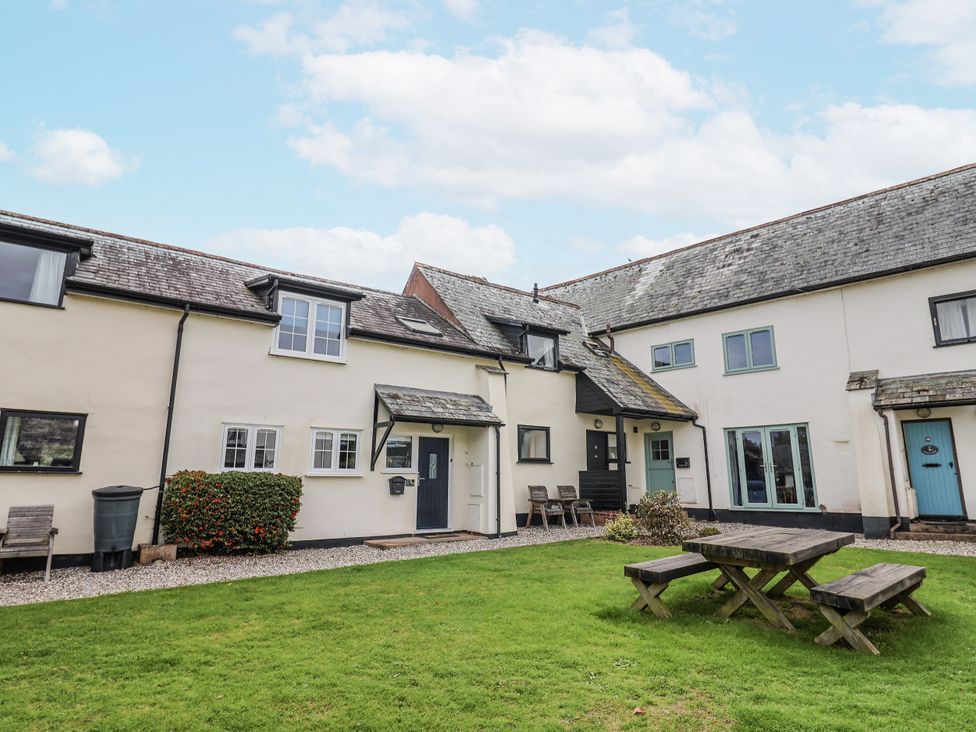 An outdoor view of a house with a garden table at Rushmoor Cottage in Colaton Raleigh