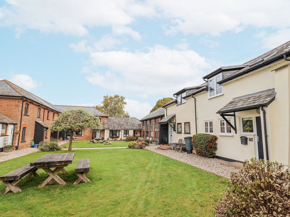 An outdoor area with buildings and a picnic bench at Rushmoor Cottage in Colaton Raleigh