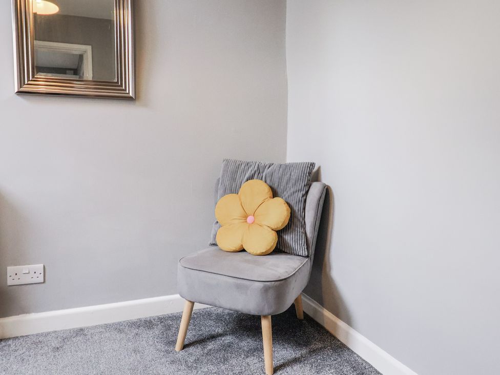 A chair with a yellow flower pillow in a living room at Rushmoor Cottage in Colaton Raleigh