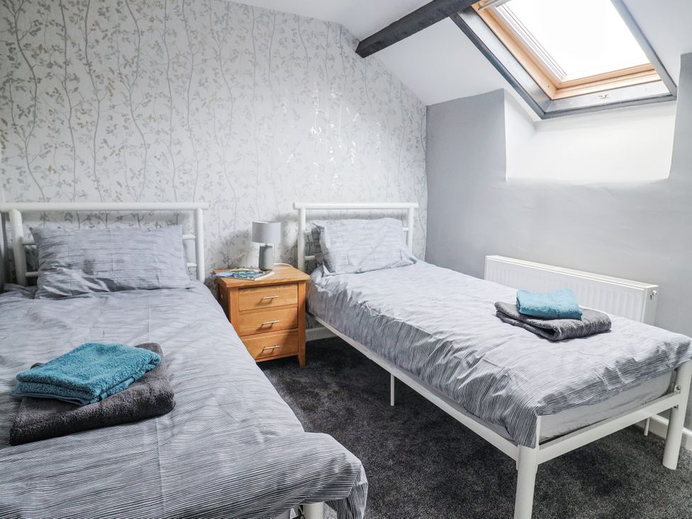 A bedroom with two beds and bedside table at Rushmoor Cottage in Colaton Raleigh