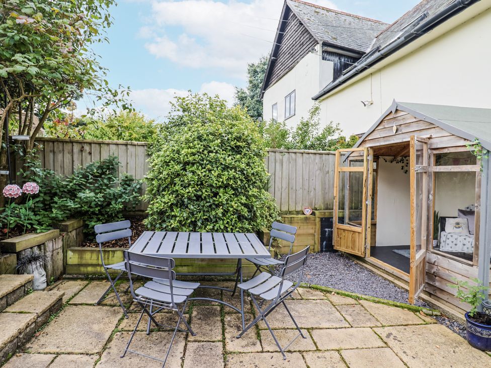 A garden with a table and chairs by a shed at Rushmoor Cottage in Colaton Raleigh