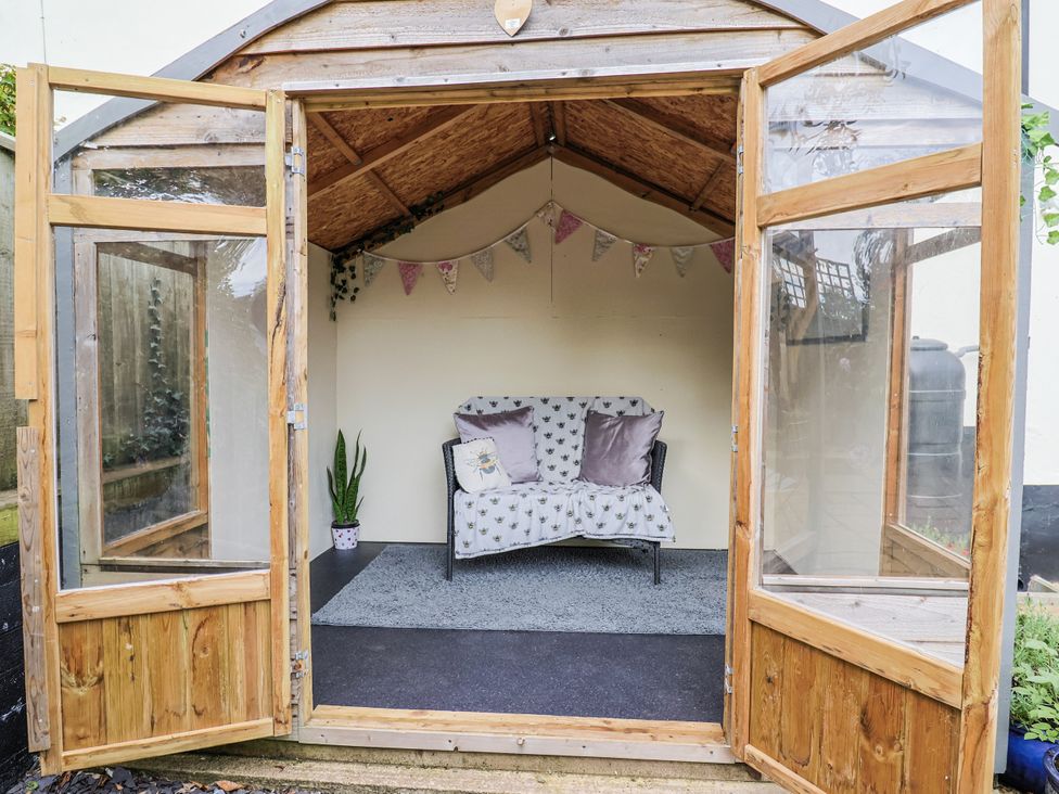 A greenhouse with a couch and potted plant at Rushmoor Cottage, Colaton Raleigh