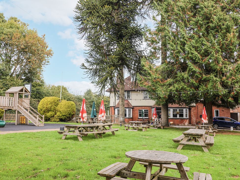 A garden with picnic tables and playground equipment at Rushmoor Cottage in Colaton Raleigh