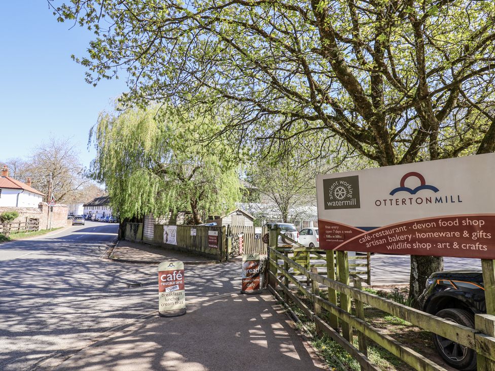 A street view with a cafe sign and trees at Otterton Mill in Colaton Raleigh