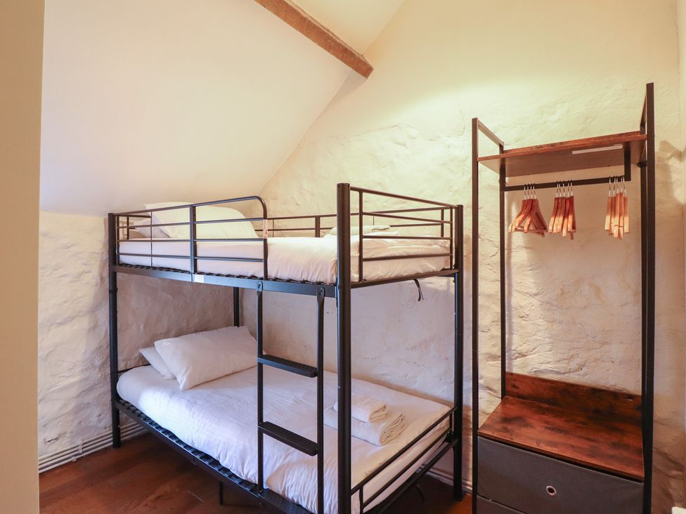 A bedroom with a bunk bed and clothes rack at 1 Fron Uchaf Parc near Bala