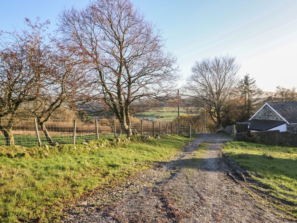 A gravel path leading to a house surrounded by trees at 1 Fron Uchaf in Parc near Bala