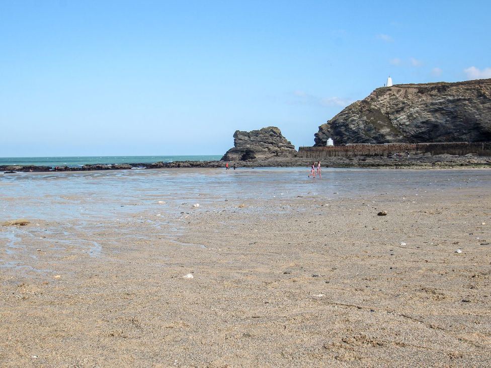 A beach scene with rocks and people wading at Klysa in Camborne