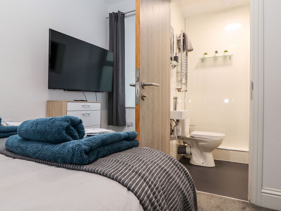 A bedroom with a television and attached bathroom at Teylu in Camborne