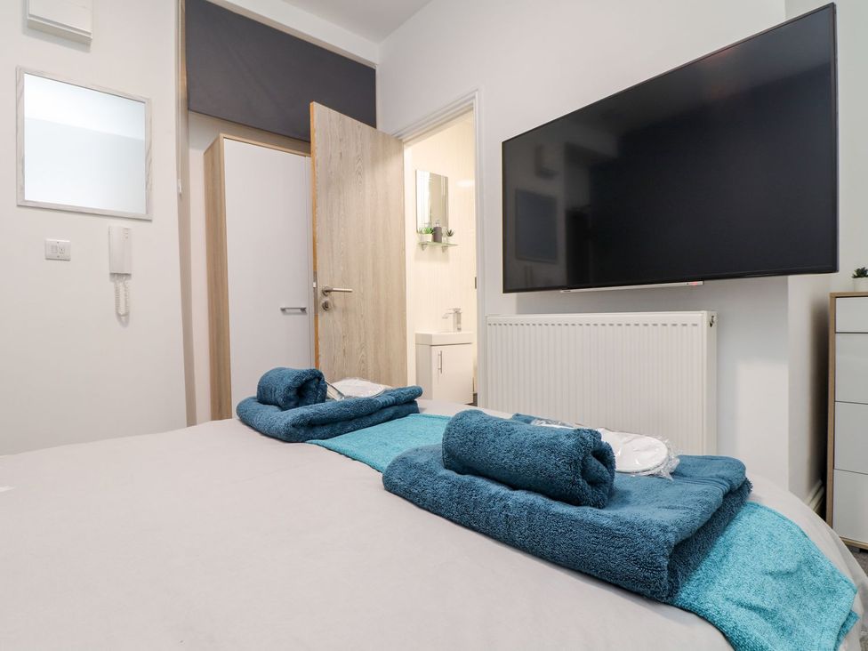 A bedroom with towels on the bed and a television on the wall at Teylu, Camborne