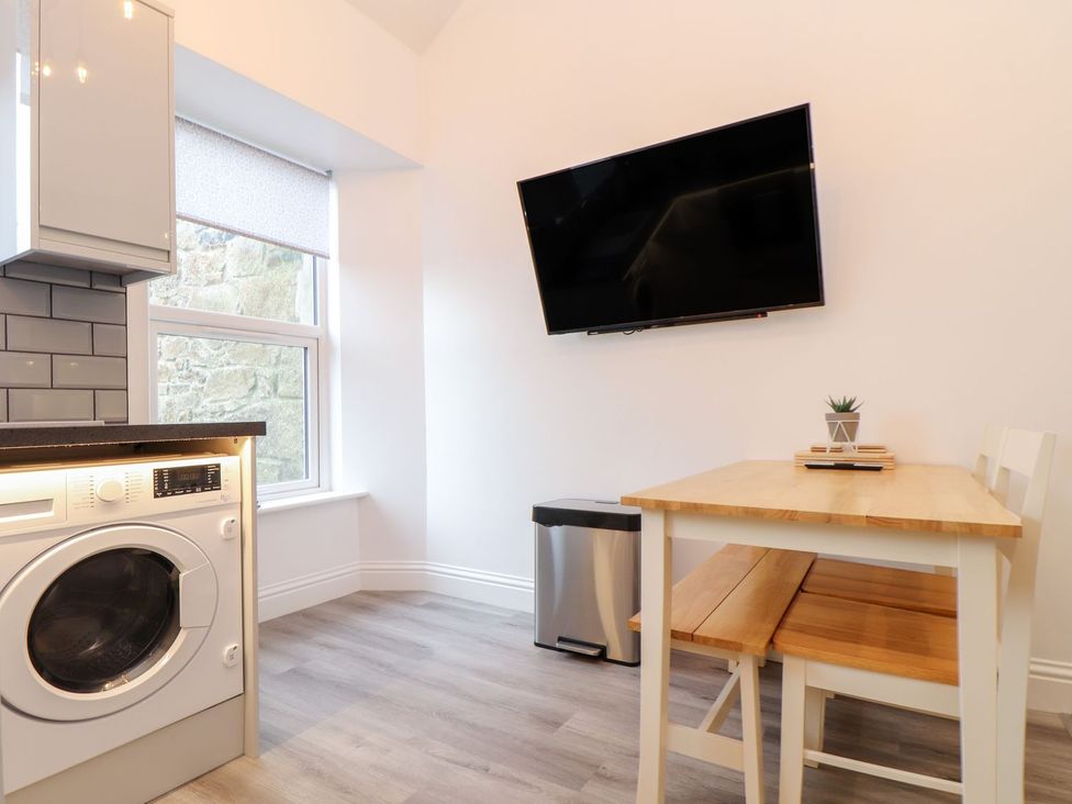 A kitchen with a washing machine and wooden table at Battell Chambers in Camborne