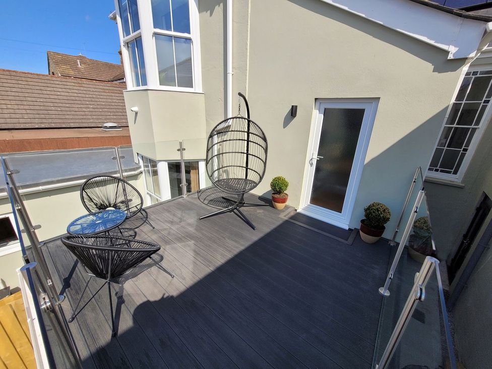 An outdoor patio with a hanging chair and a coffee table at Daniel Chambers in Camborne