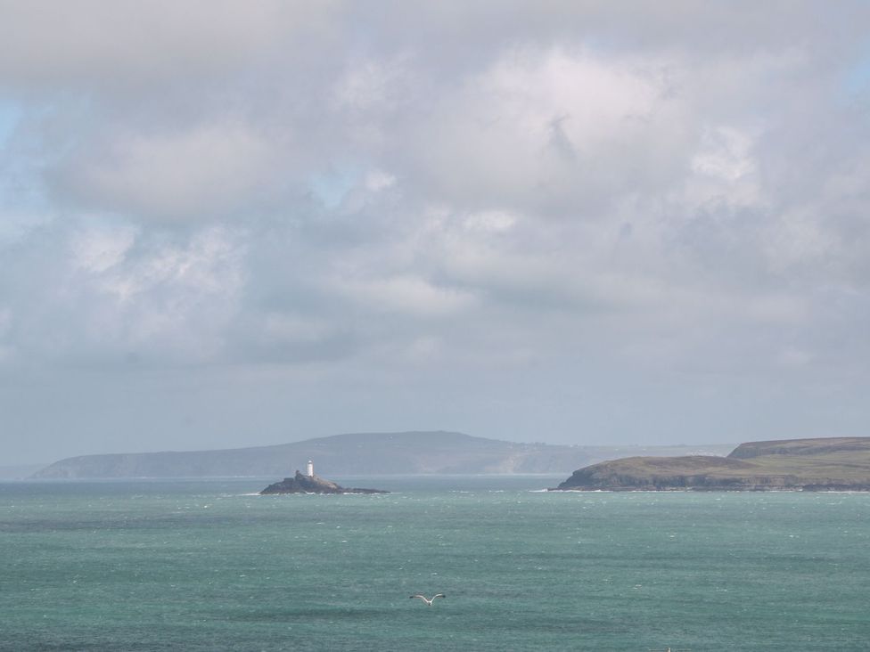 A view of a lighthouse on an island in the ocean with clouds in the sky at Daniel Chambers in Camborne