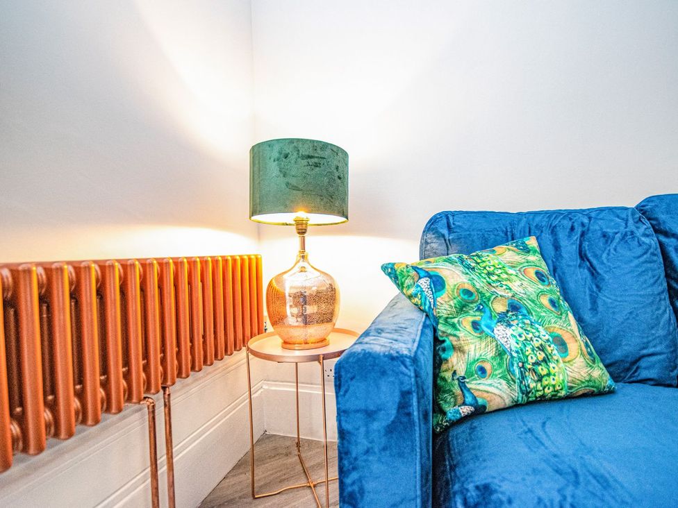 A living room with a blue sofa and a table lamp at Mews Retreat in Camborne