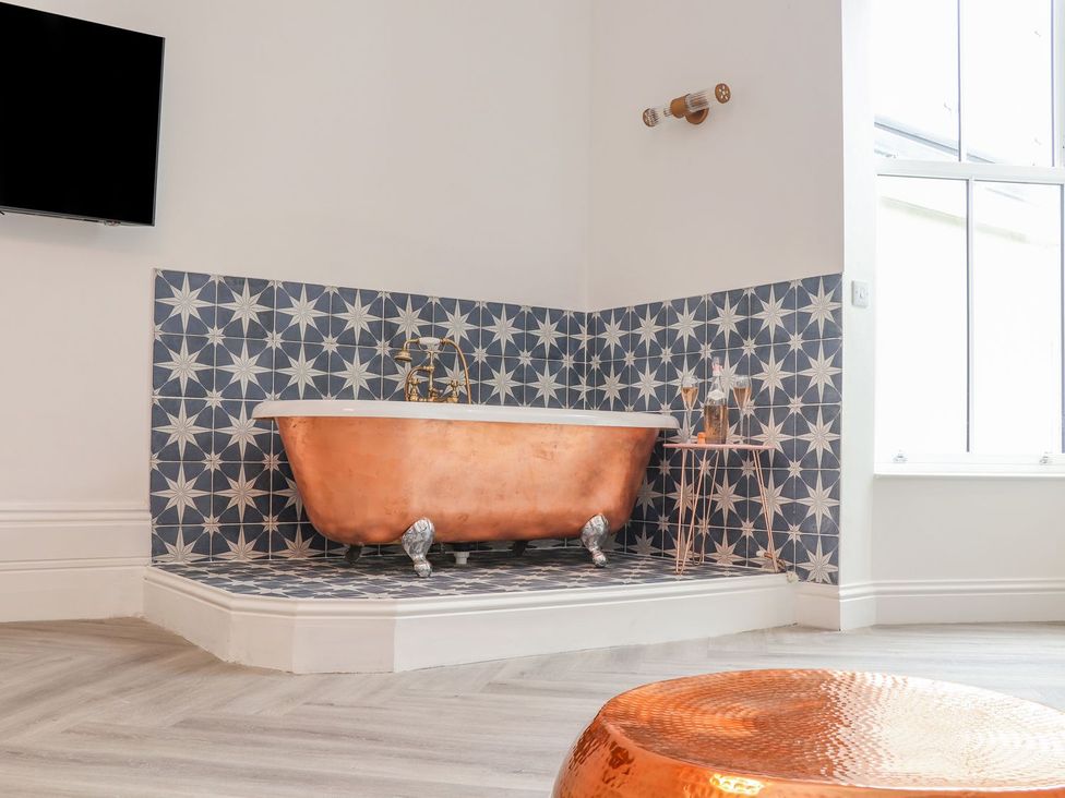 A bathroom with a copper bathtub and tiled wall at Mews Retreat Camborne