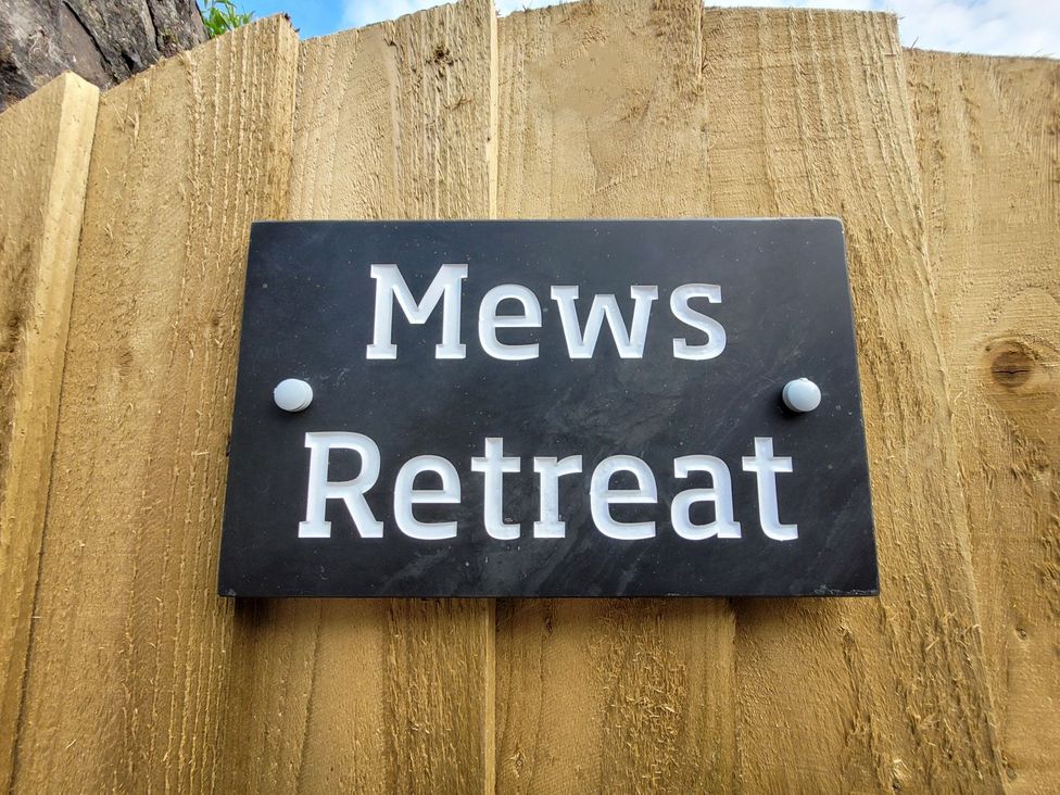 A sign for Mews Retreat on a wooden fence at Mews Retreat in Camborne