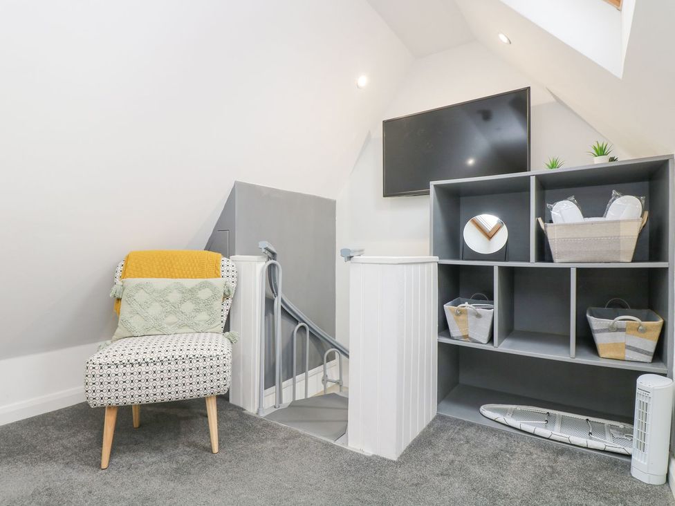 A snug area with a chair, television, and shelf at The Snug in Camborne