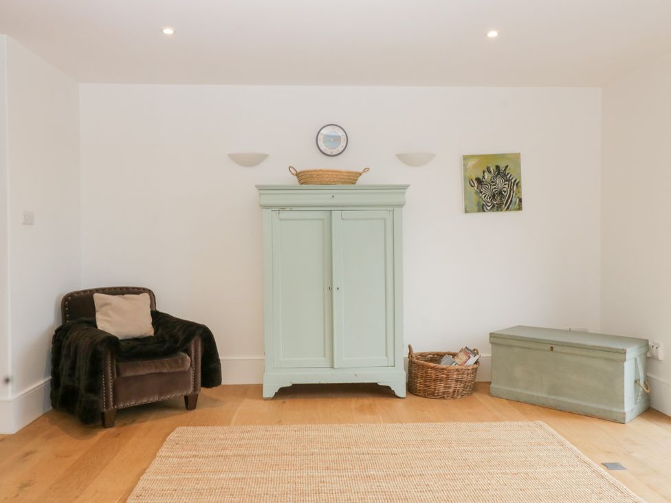A sitting room with a wardrobe and armchair at Spring View in Tetbury