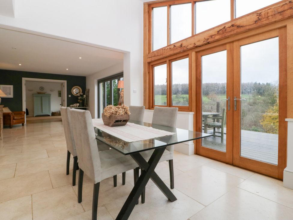 A dining room with a glass table and chairs at Spring View in Tetbury