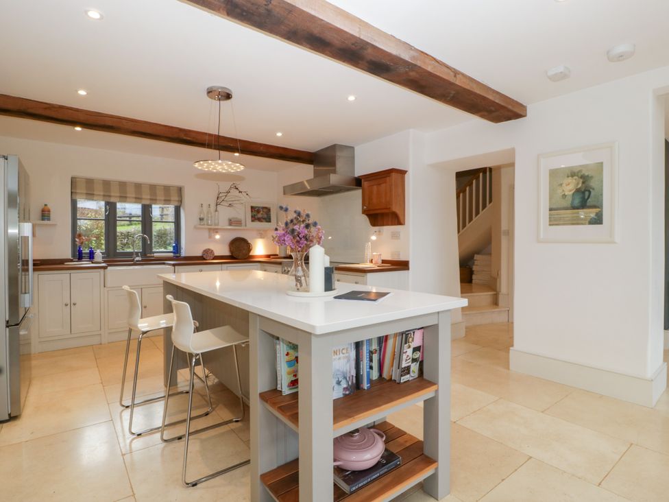 A kitchen with an island and stools at Spring View in Tetbury