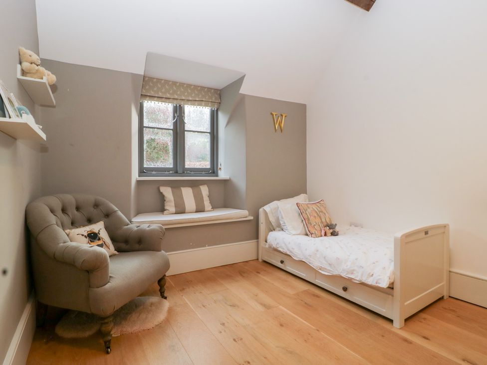 A bedroom with a bed and an armchair at Spring View in Tetbury