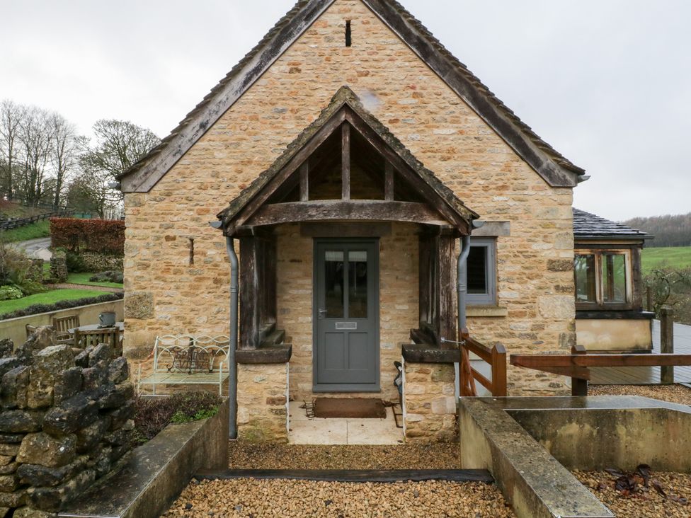 An entrance of a stone house with a wooden door at Spring View, Tetbury