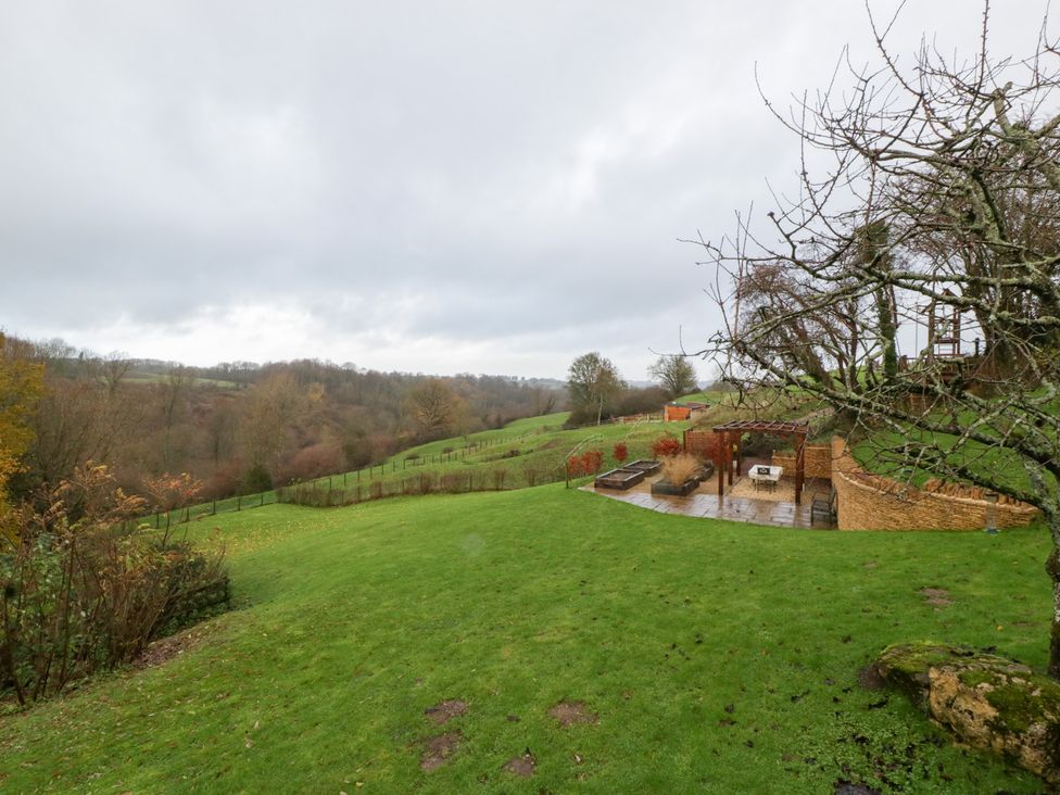 A landscaped outdoor area with a seating patio and trees at Spring View in Tetbury