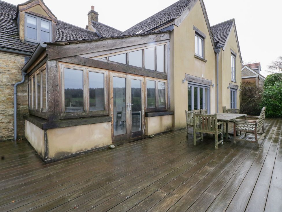 A house exterior with a wooden deck and dining set at Spring View in Tetbury